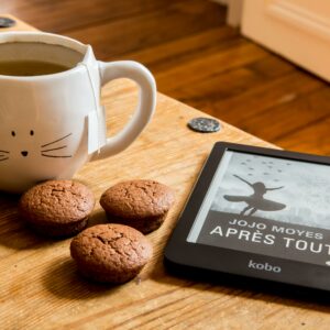 A cozy scene with tea, muffins, and an e-reader on a wooden table.